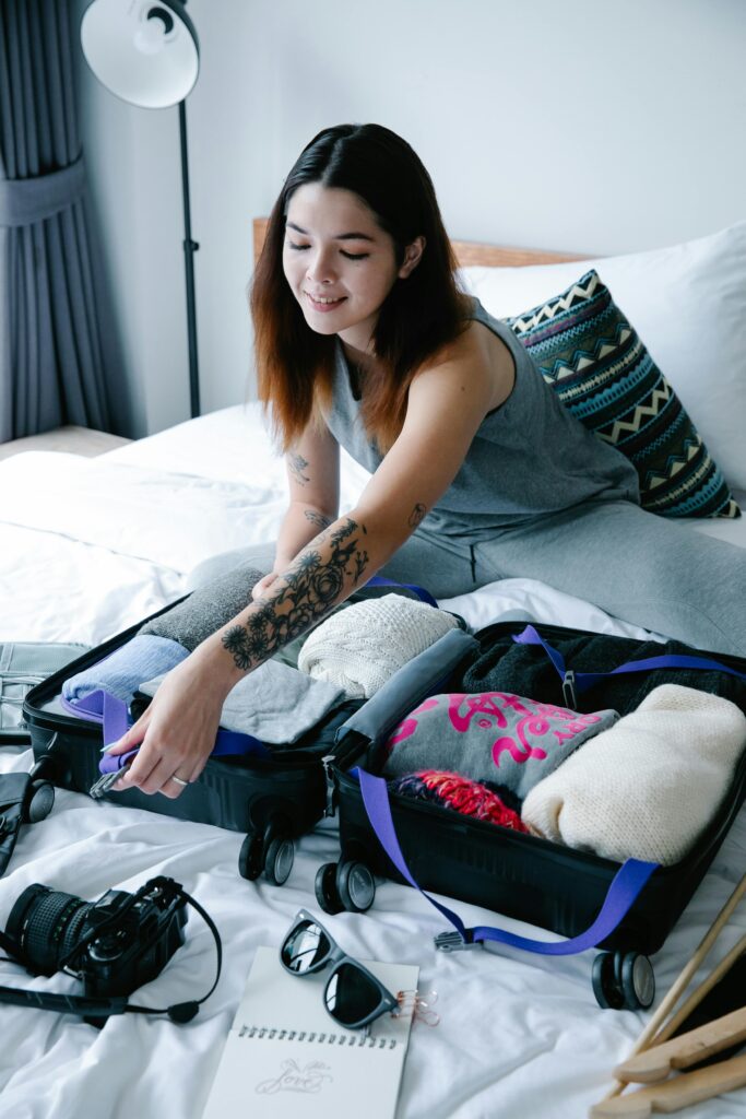 Woman with tattoos packing a suitcase in a modern bedroom setting.