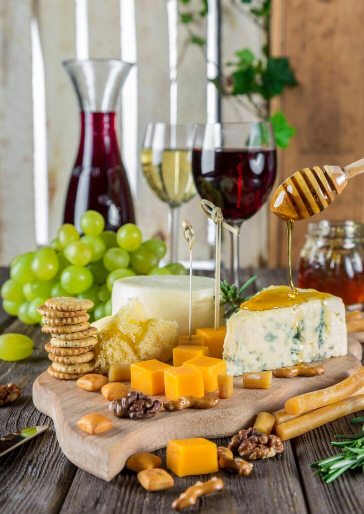 Sophisticated cheese platter with assorted wines, grapes, honey, and nuts.